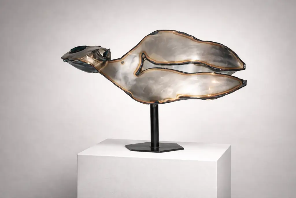 "Woman" by Ferrán Soriano, a horizontal contemporary sculpture made of welded stainless steel plates. This 64x95 cm artwork features a modern industrial aesthetic with metallic textures and a unique structural composition. «Mujer», de Ferrán Soriano, es una escultura contemporánea horizontal realizada con placas de acero inoxidable soldadas. Esta obra de 64 x 95 cm presenta una estética industrial moderna con texturas metálicas y una composición estructural única.