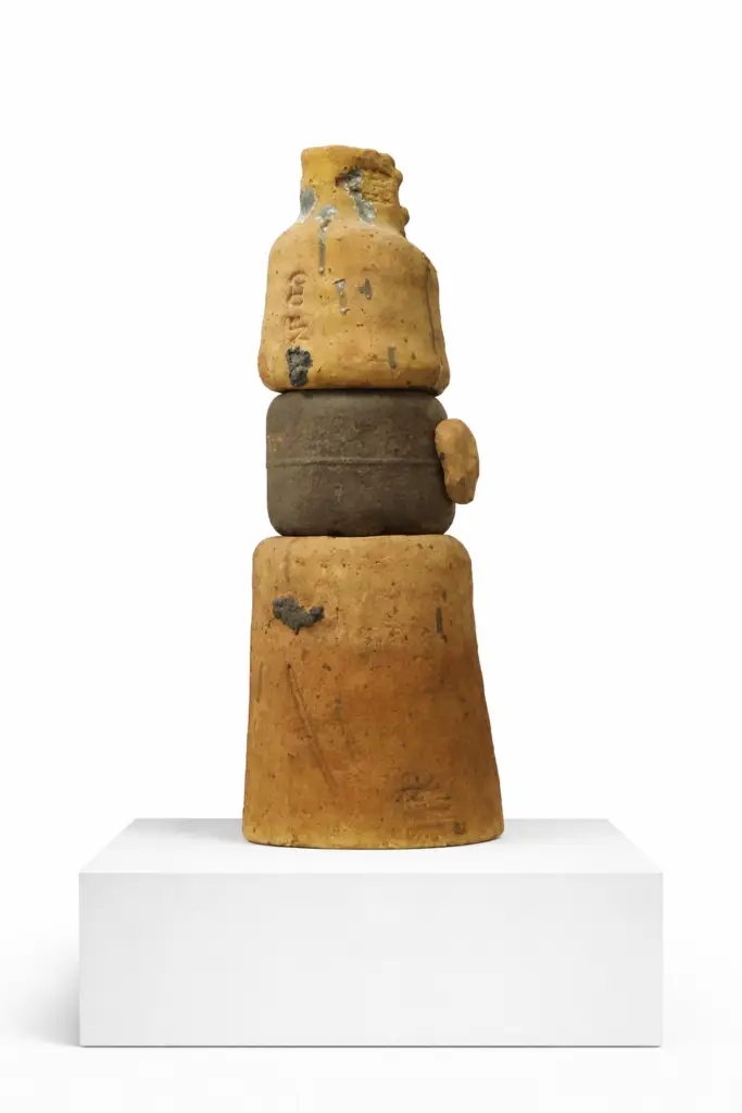 A vertical contemporary sculpture titled "Untitled" by Daniel Gutiérrez Adán, crafted from fired refractory clay and iron. The piece features an industrial, textured aesthetic with earthy clay tones contrasted against dark iron elements, standing 96 cm tall on a slim, upright composition. Escultura vertical contemporánea titulada "Sin título", de Daniel Gutiérrez Adán, elaborada con arcilla refractaria cocida y hierro. La pieza presenta una estética industrial y texturizada, con tonos terrosos de arcilla que contrastan con elementos de hierro oscuro. Mide 96 cm de altura y se asienta sobre una base esbelta y vertical.