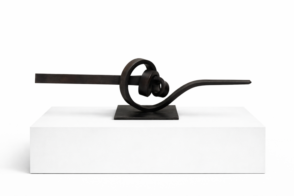 Knot (Artwork ID 304) by José Antonio Olarte, a horizontal contemporary sculpture in forged iron. This 90 cm wide minimalist metal artwork features a knotted industrial design with raw textures and a strong horizontal composition, suitable for wall or pedestal display. Nudo (Referencia 304) de José Antonio Olarte, una escultura horizontal contemporánea en hierro forjado. Esta pieza minimalista de 90 cm de ancho presenta un diseño industrial anudado con texturas rugosas y una marcada composición horizontal, ideal para montaje en pared o pedestal.