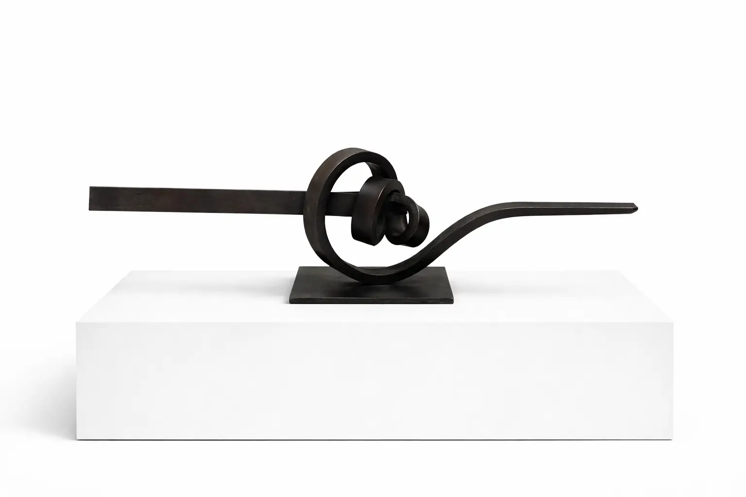 Knot (Artwork ID 304) by José Antonio Olarte, a horizontal contemporary sculpture in forged iron. This 90 cm wide minimalist metal artwork features a knotted industrial design with raw textures and a strong horizontal composition, suitable for wall or pedestal display. Nudo (Referencia 304) de José Antonio Olarte, una escultura horizontal contemporánea en hierro forjado. Esta pieza minimalista de 90 cm de ancho presenta un diseño industrial anudado con texturas rugosas y una marcada composición horizontal, ideal para montaje en pared o pedestal.